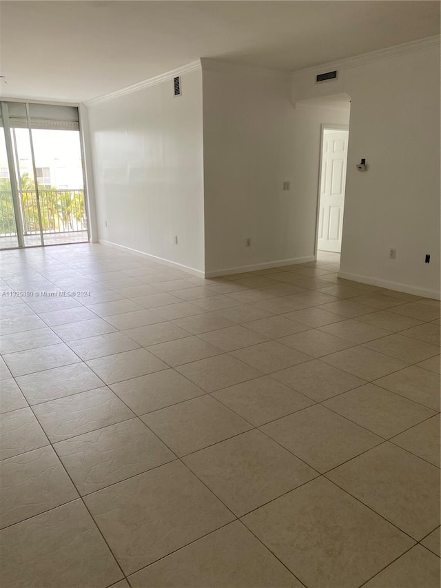 spare room featuring expansive windows, ornamental molding, and light tile floors