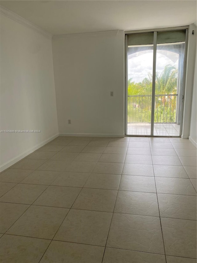 tiled spare room featuring expansive windows and ornamental molding