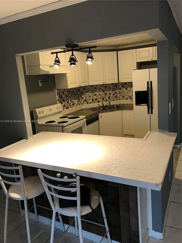 kitchen with white cabinets, white appliances, tile patterned floors, and a breakfast bar area