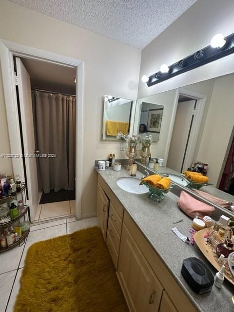 bathroom featuring tile patterned flooring, vanity, and a textured ceiling