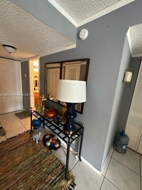 hallway featuring light tile patterned floors, a textured ceiling, and crown molding