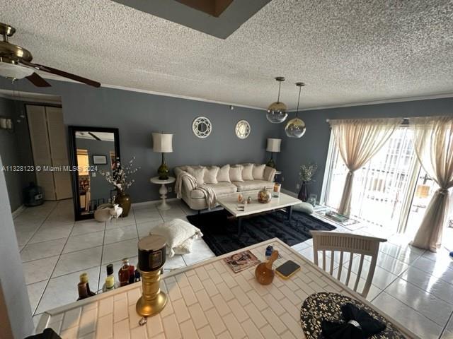 tiled living room featuring ceiling fan, crown molding, and a textured ceiling