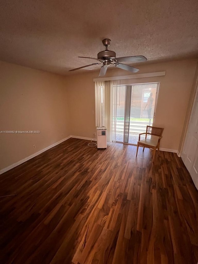 empty room with ceiling fan, a textured ceiling, and dark hardwood / wood-style flooring