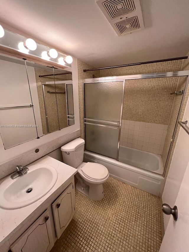 full bathroom with toilet, vanity, bath / shower combo with glass door, and tile flooring