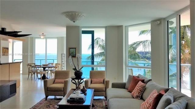 living room featuring plenty of natural light, a water view, and a wall of windows