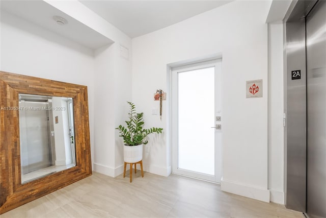 doorway to outside with light tile floors and elevator