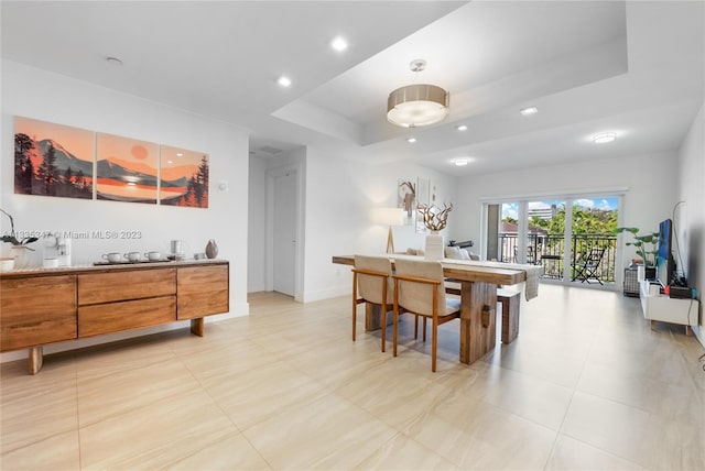 dining area with a raised ceiling and light tile floors