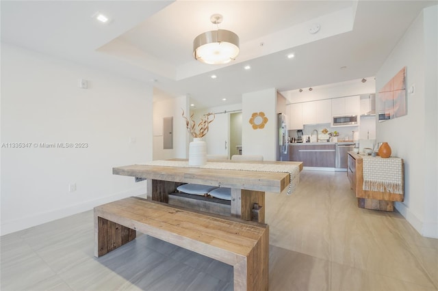 tiled dining space with a tray ceiling and sink