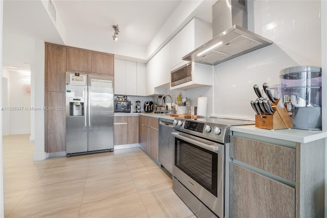 kitchen with stainless steel appliances, wall chimney range hood, light tile flooring, white cabinets, and sink