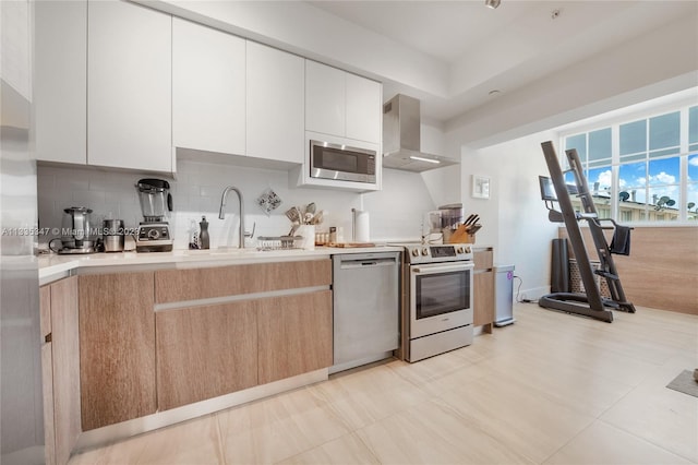 kitchen with white cabinetry, wall chimney exhaust hood, light tile flooring, and stainless steel appliances