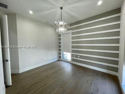 spare room featuring a notable chandelier and dark hardwood / wood-style flooring