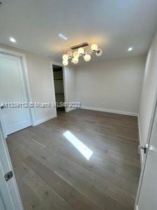 empty room with a notable chandelier and dark hardwood / wood-style flooring