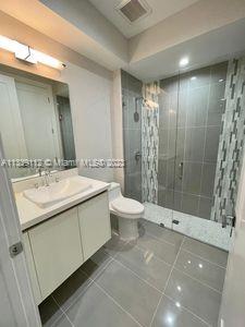 bathroom featuring walk in shower, tile flooring, oversized vanity, and toilet