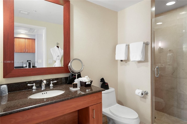 bathroom with a shower with door, vanity with extensive cabinet space, and toilet