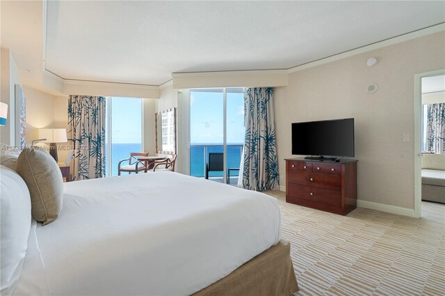 bedroom with light colored carpet, ornamental molding, multiple windows, and a water view