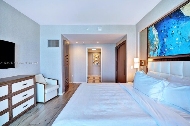 bedroom with light hardwood / wood-style floors and a closet