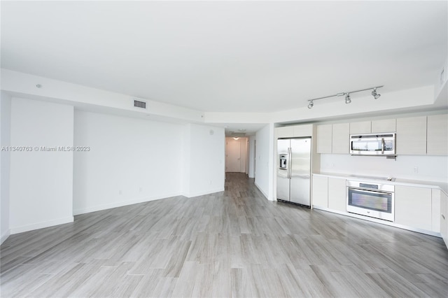 unfurnished living room with track lighting and light hardwood / wood-style flooring