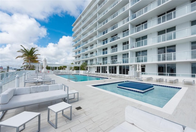 view of swimming pool featuring a patio, an outdoor hangout area, and a hot tub