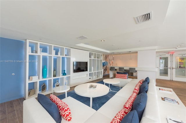 living room with a raised ceiling and hardwood / wood-style flooring