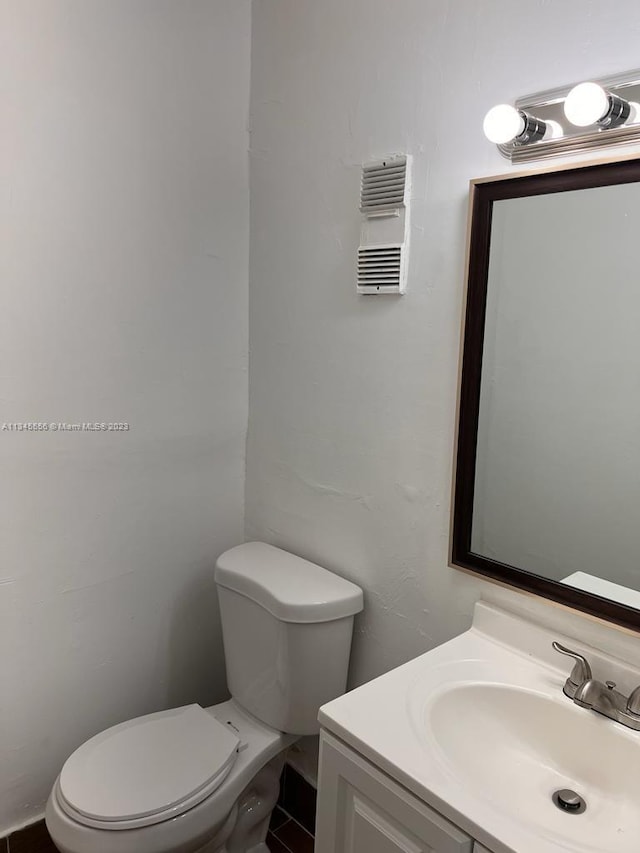 bathroom featuring toilet, vanity, and tile flooring