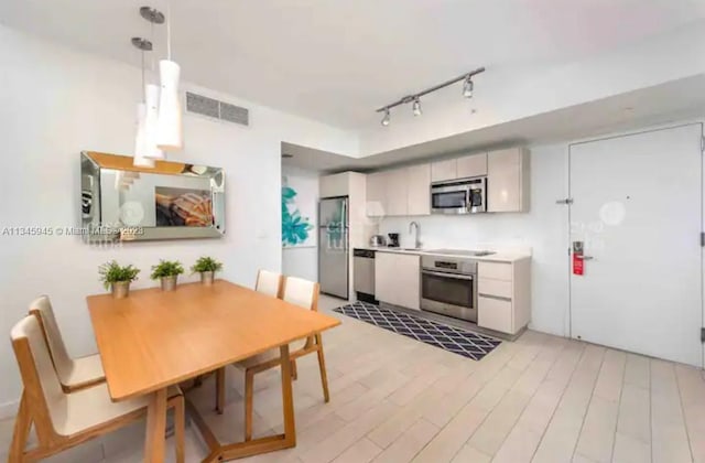 dining room with rail lighting, sink, and light hardwood / wood-style flooring