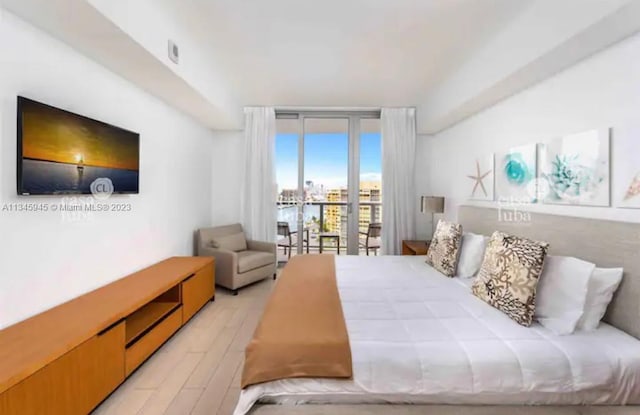 bedroom featuring a wall of windows, access to outside, and light hardwood / wood-style flooring