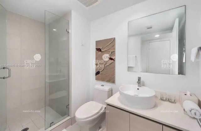 bathroom featuring oversized vanity, toilet, and a shower with door