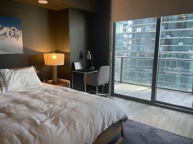 bedroom with expansive windows, access to exterior, and light hardwood / wood-style floors