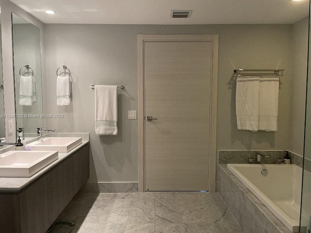 bathroom featuring tiled bath, tile floors, and dual bowl vanity