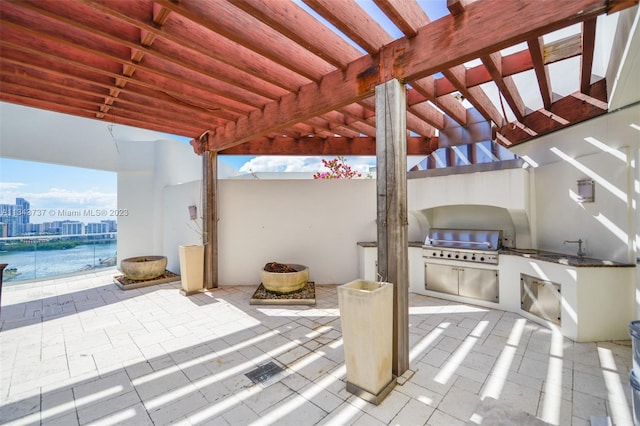 view of patio with area for grilling, a pergola, grilling area, a water view, and sink