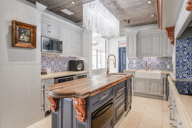 kitchen with an inviting chandelier, wooden ceiling, stainless steel microwave, and sink