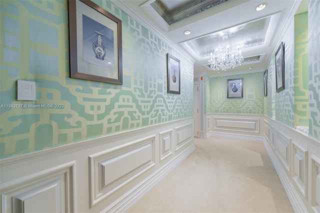 hallway with crown molding, an inviting chandelier, and light colored carpet