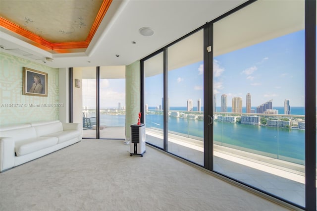 interior space with crown molding, a water view, expansive windows, and a tray ceiling