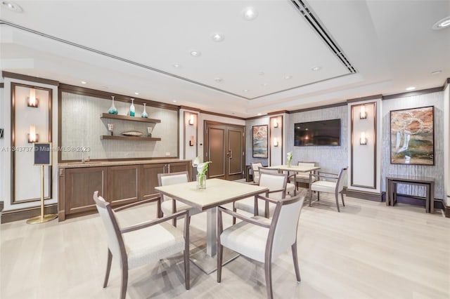 dining room with a raised ceiling and light wood-type flooring