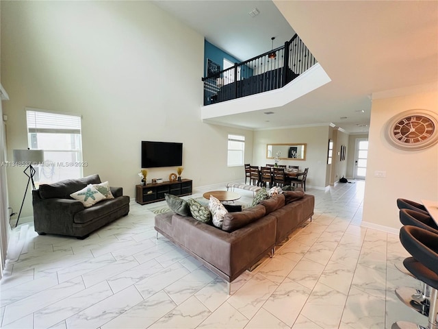 living room with crown molding, a towering ceiling, and plenty of natural light