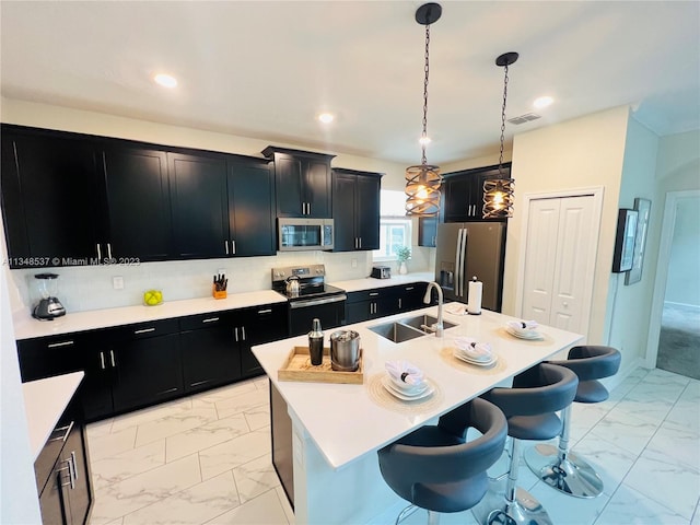 kitchen featuring pendant lighting, sink, an island with sink, and stainless steel appliances