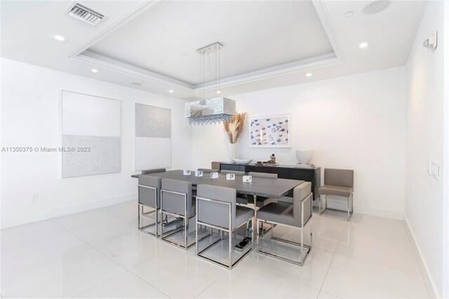 dining area with light tile floors and a raised ceiling