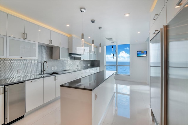 kitchen featuring pendant lighting, light tile floors, high quality fridge, tasteful backsplash, and sink