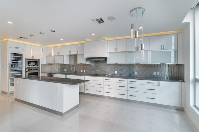 kitchen featuring appliances with stainless steel finishes, decorative light fixtures, tasteful backsplash, and white cabinetry