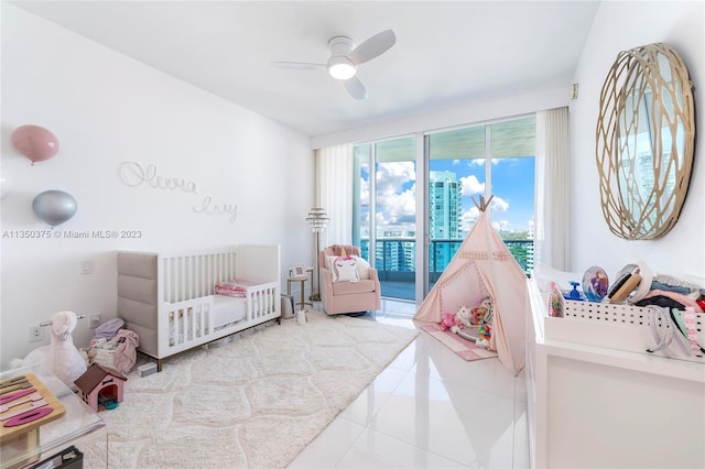 tiled bedroom featuring access to outside, a nursery area, and ceiling fan