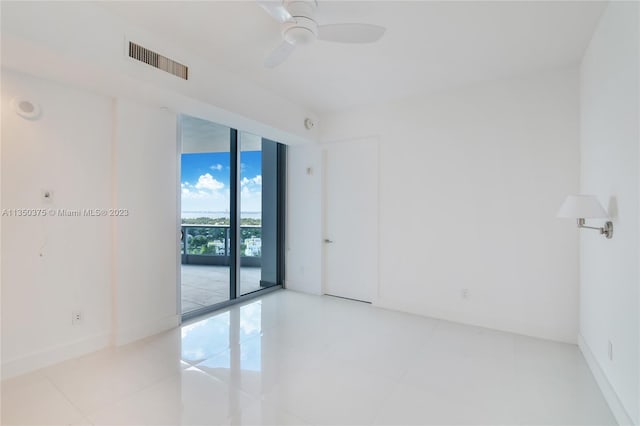 tiled spare room with floor to ceiling windows and ceiling fan