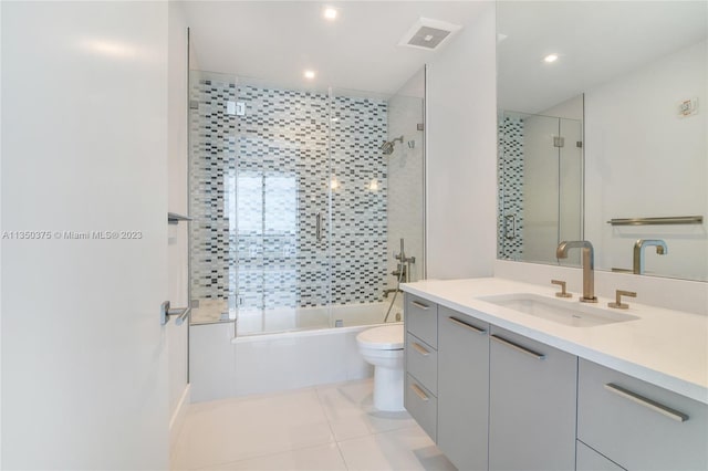 full bathroom with toilet, tile flooring, oversized vanity, and bath / shower combo with glass door