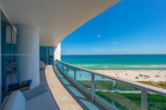 balcony with a water view and a view of the beach