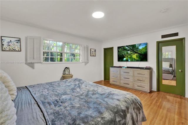 bedroom with crown molding and light hardwood / wood-style flooring