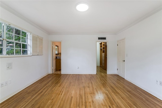 spare room featuring ornamental molding and light wood-type flooring