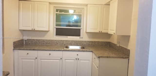 kitchen featuring white cabinets, sink, and dark stone countertops