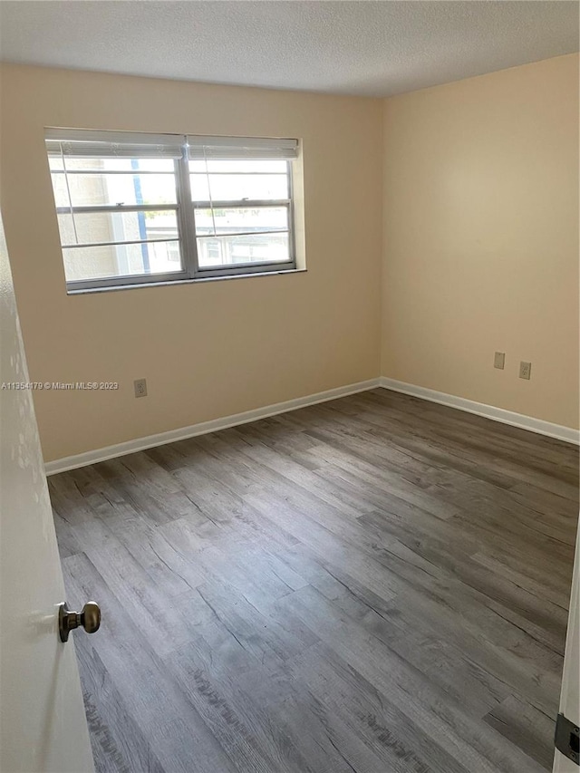 empty room featuring plenty of natural light, a textured ceiling, and hardwood / wood-style flooring