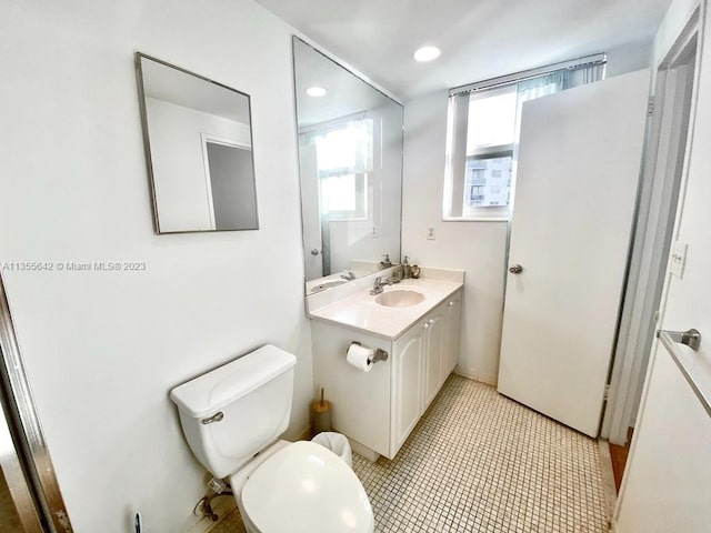 bathroom with toilet, vanity with extensive cabinet space, and tile flooring