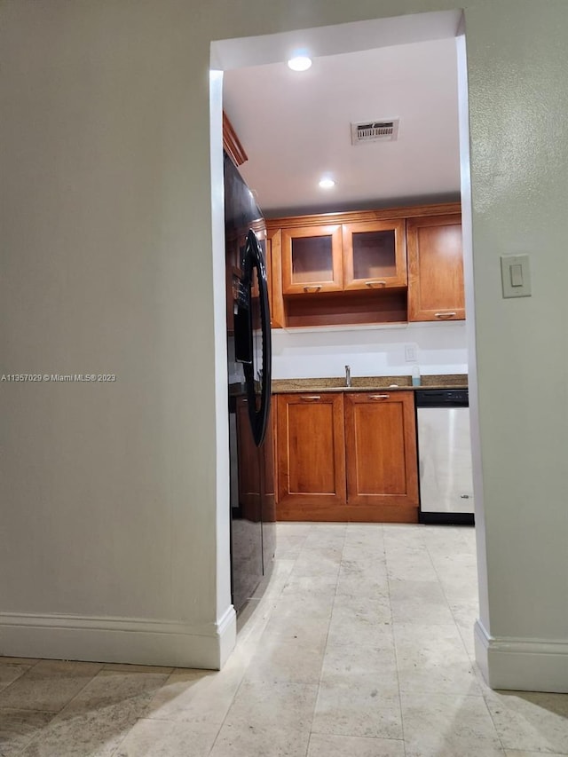 interior space featuring black fridge, light tile patterned floors, and stainless steel dishwasher