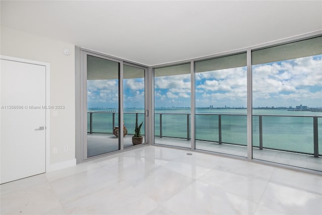 empty room with a water view, expansive windows, and light tile floors